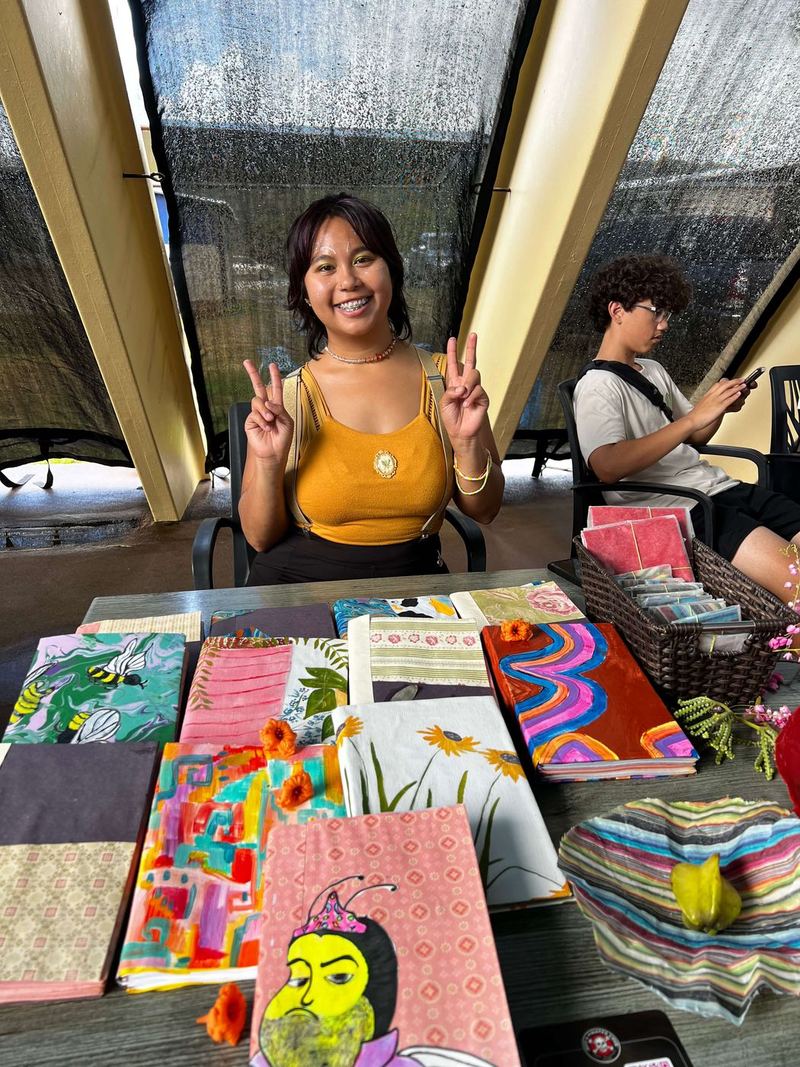 A craft vendor with a table of colorful handmade notebooks