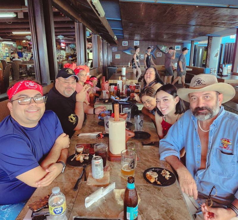 A table of regulars in red bandanas smiling in the restaurant