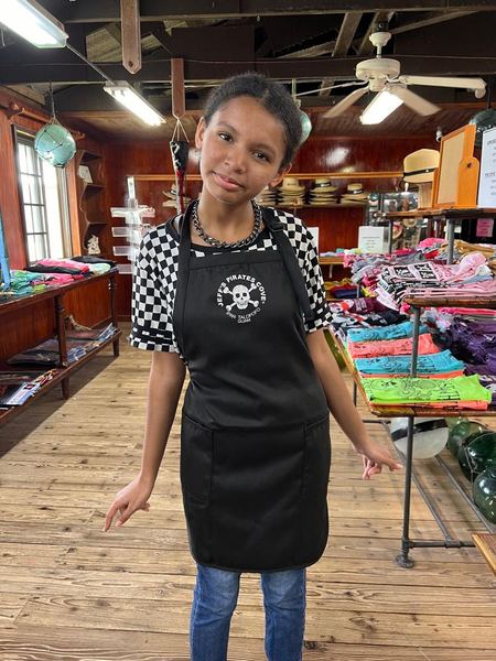 A black JPC apron with the skull logo, modeled in the gift shop