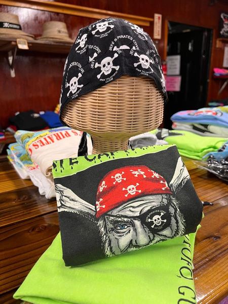 A black skull-print JPC bandana on a wicker head, above a pirate-face print