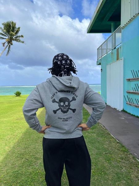 The back of a gray JPC hoodie with the skull logo, worn by the ocean