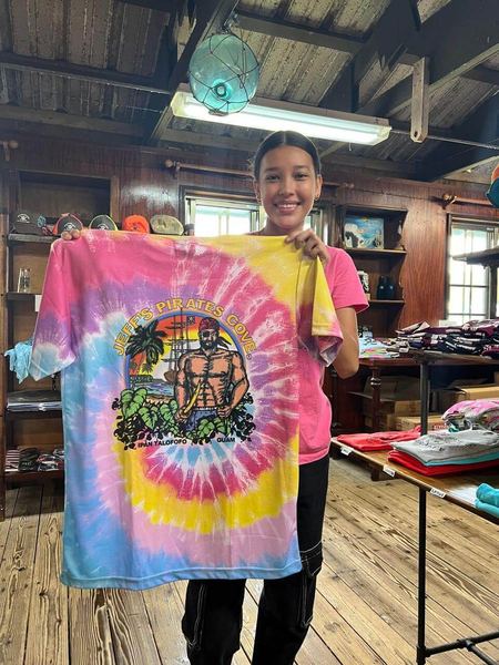 A rainbow tie-dye Jeff's Pirates Cove tee held up in the gift shop
