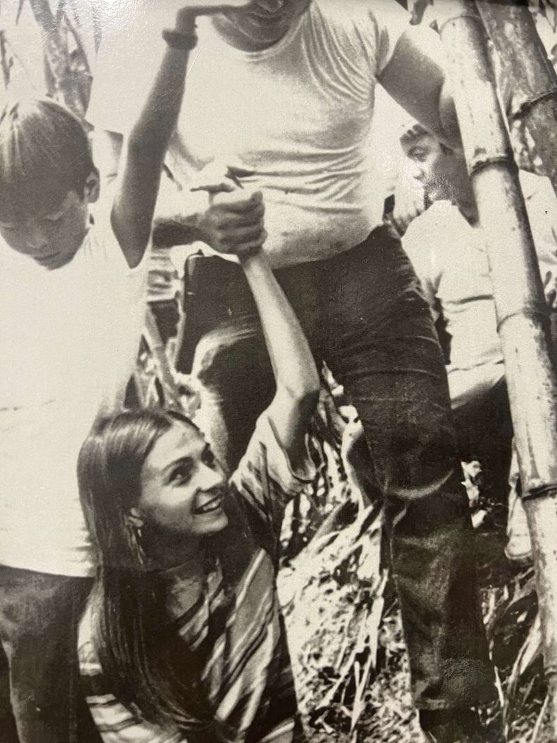 A smiling young woman and local boys crowding around a man in a white T-shirt